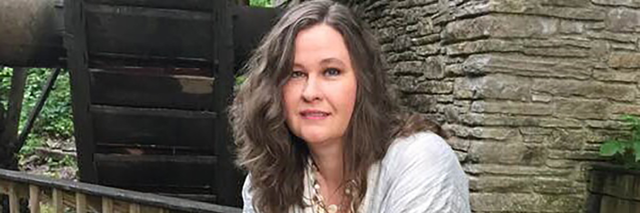 Mary standing on a wooden deck outdoors.