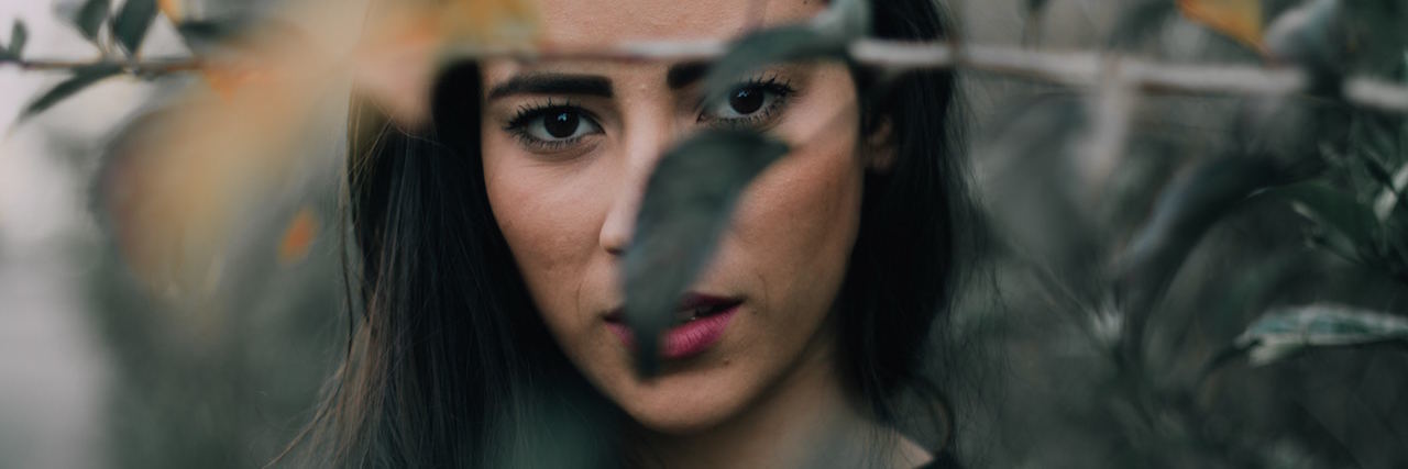 Depression: When Anhedonia Takes Away Your Personality A woman peaking from behind a tree