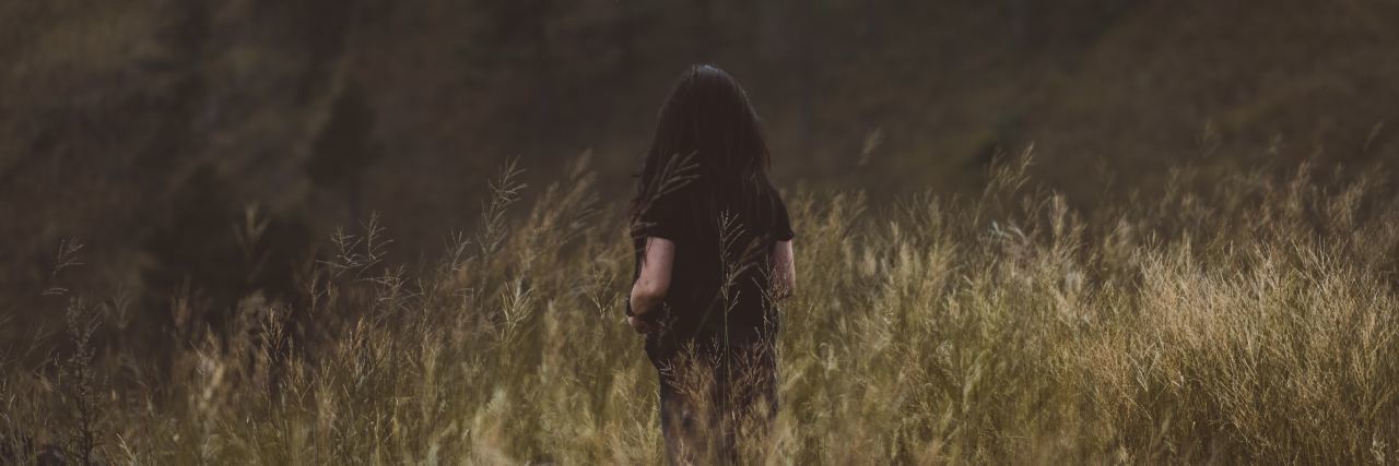 What My Loved Ones Should Know and Understand About My Depression photo of dark haired woman from behind standing in long grass