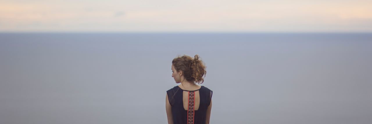Living with Functional Neurological Disorder and Dealing With Emotions woman looking to the side, in front of the sky and water