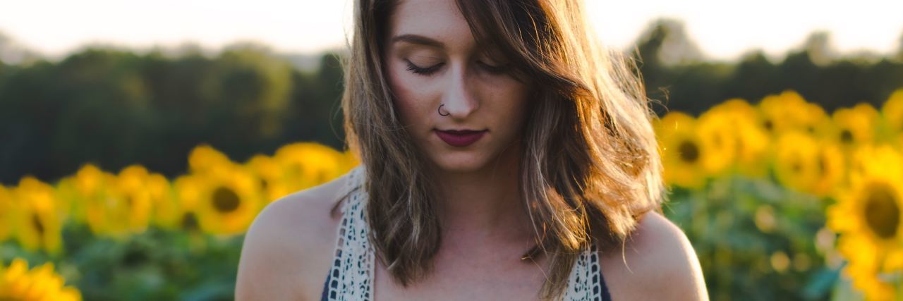 Borderline Personality Disorder Symptoms With Examples photo of woman standing in field of sunflowers looking down with one in her hand