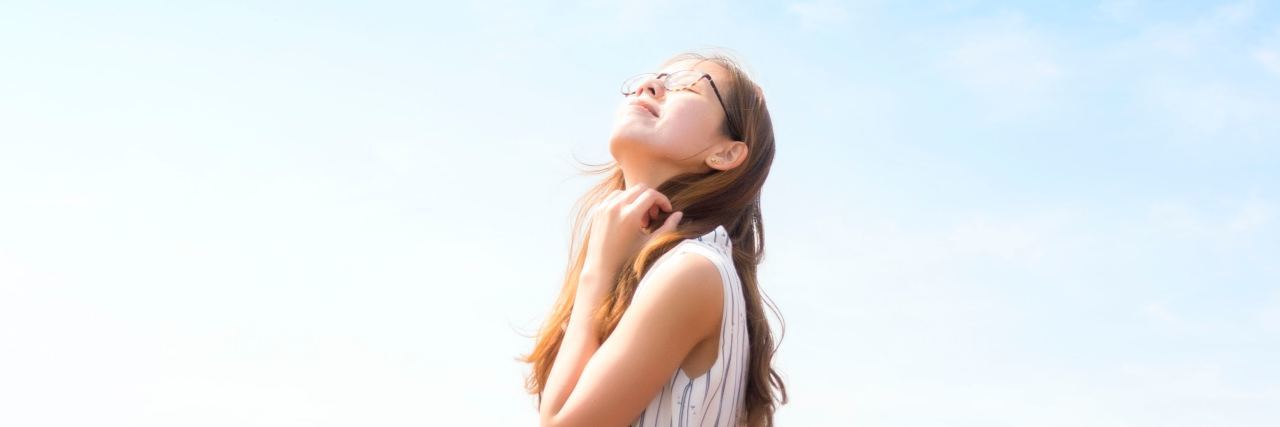 photo of young woman in flower meadow looking happy with hands in hair