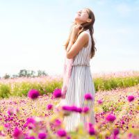 photo of young woman in flower meadow looking happy with hands in hair