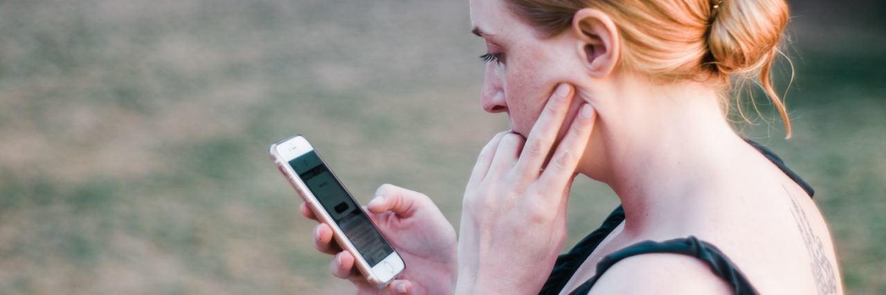 Volunteering for Shout: The UK's First Free Crisis Text Line photo of young woman outdoors possibly upset and looking at her smartphone