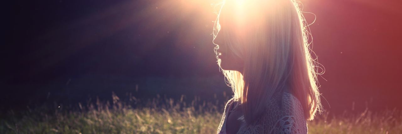photo of woman silhouetted by sunlight and light flare