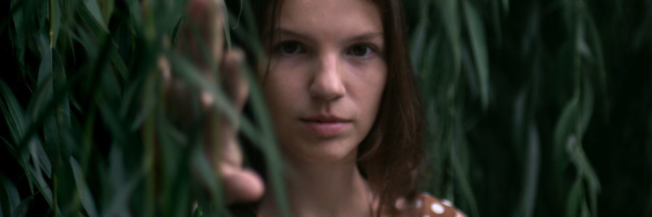 photo of woman standing in leaves looking into camera