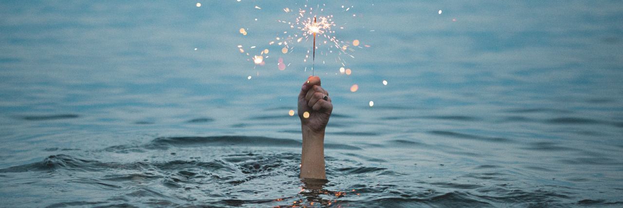 How to Stop Intrusive Thoughts photo of hand rising out of ocean holding a sparkler