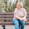 photo of woman sitting on bench smiling with eyes closed