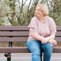 photo of woman sitting on bench smiling with eyes closed
