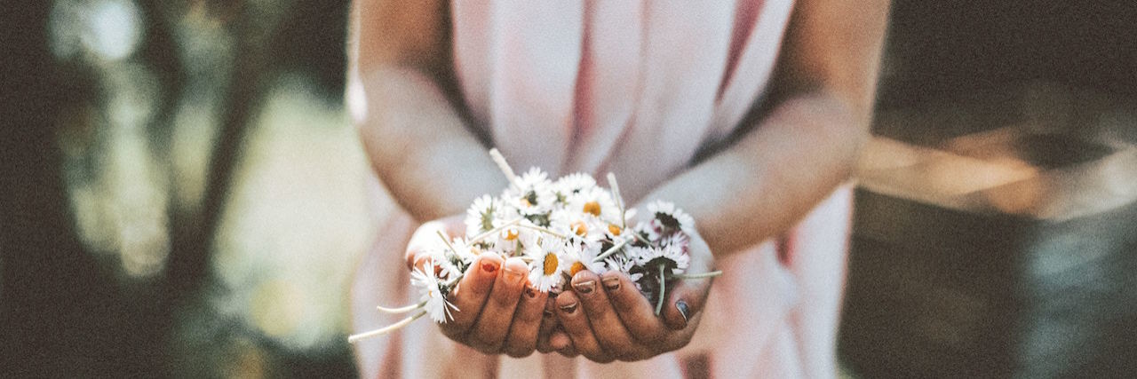 Feeling Depressed and Not Good Enough Even When Good Things Happen A woman in a pink dress holding white daisies in her hand