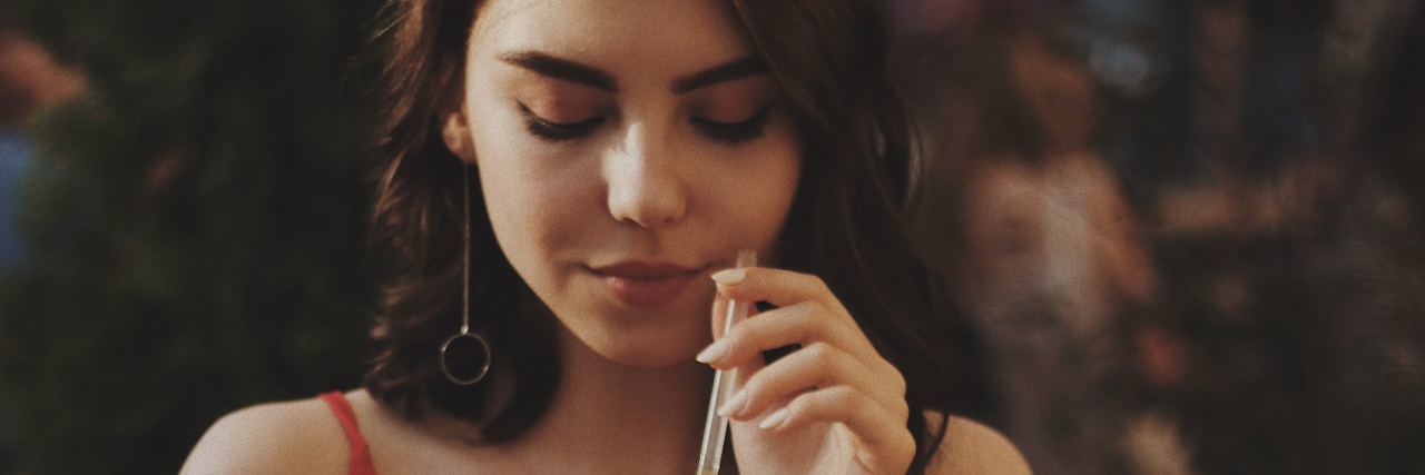 When Loved Ones Think Eating Disorder Recovery Means ‘Cured’ photo of woman in warm light drinking with straw and with burger sitting on table in front of her