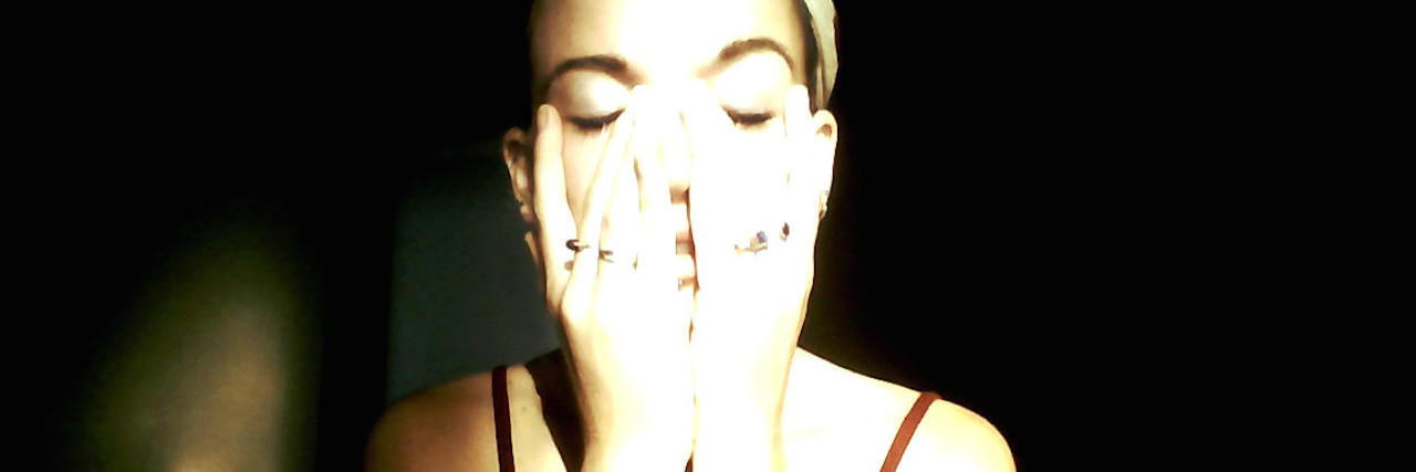 Why Touch Is Important in Mental Health Recovery A woman covered in light, with her hand over her face.