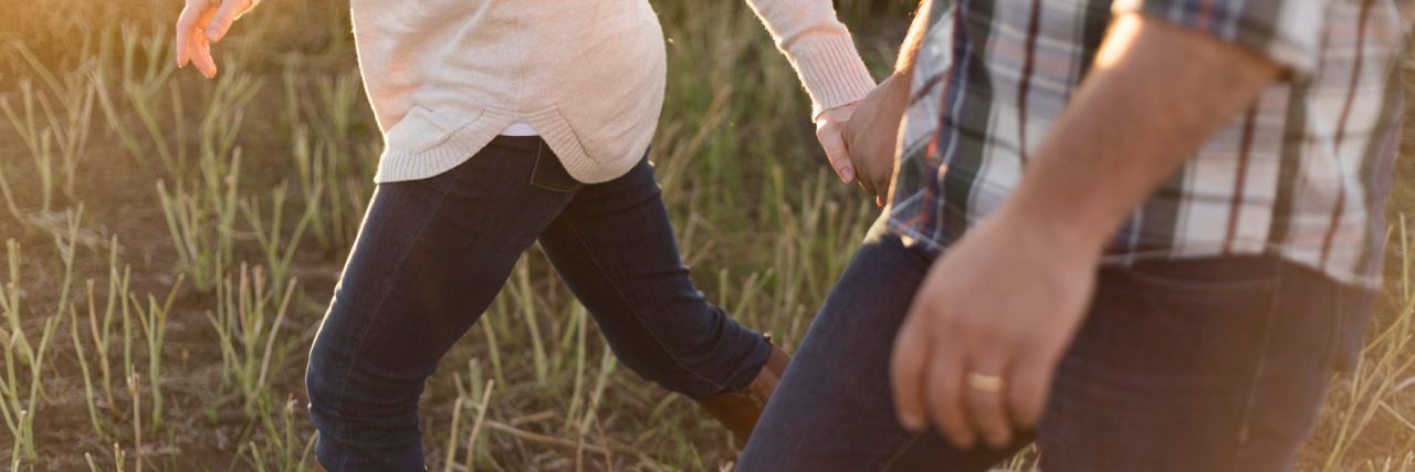 Love With a Mental Illness Is the Same close up photo of woman and man walking through field at sunset holding hands