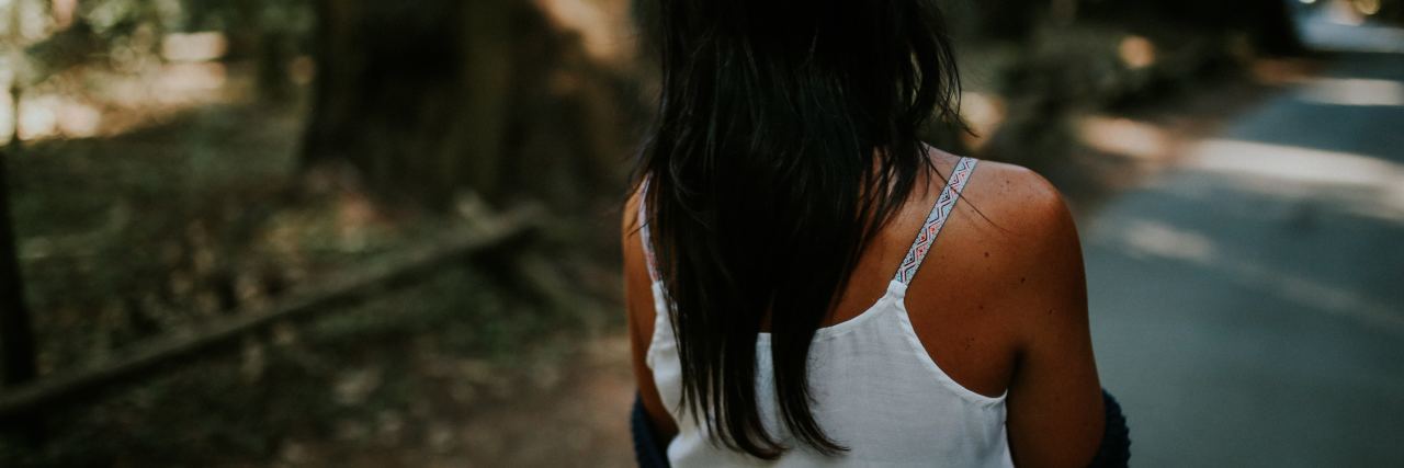 Learning Empathy After Chronic Illness Diagnosis Woman walking on a street, focus on her back