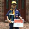 Boy posing with Scout trophy and Scout certificate