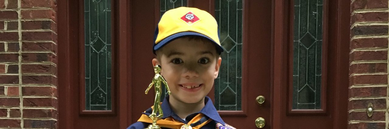 Reasons Scouting Has Been Beneficial for My Son With a Disability Boy posing with Scout trophy and Scout certificate