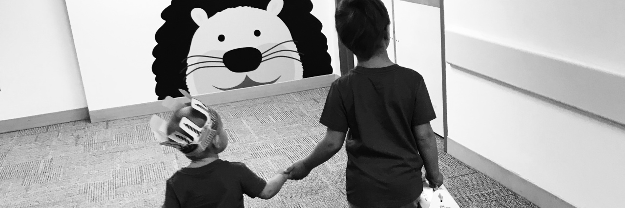 How to Talk About Your Child's Cancer With Their Healthy Siblings two brothers holding hands walking down hallway