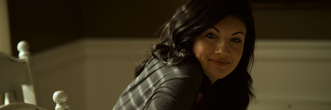 Studying Psychology to Understand My Own Mental Illness photo of woman with dark hair sitting at table and looking into camera