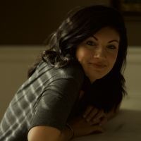photo of woman with dark hair sitting at table and looking into camera