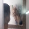 photo of young blonde woman looking into steamy bathroom mirror