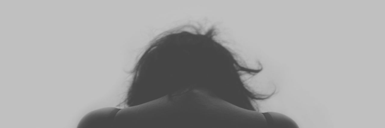 Managing a Rare Disease and Mental Health Diagnosis photo of the back of a woman, with her head looking down