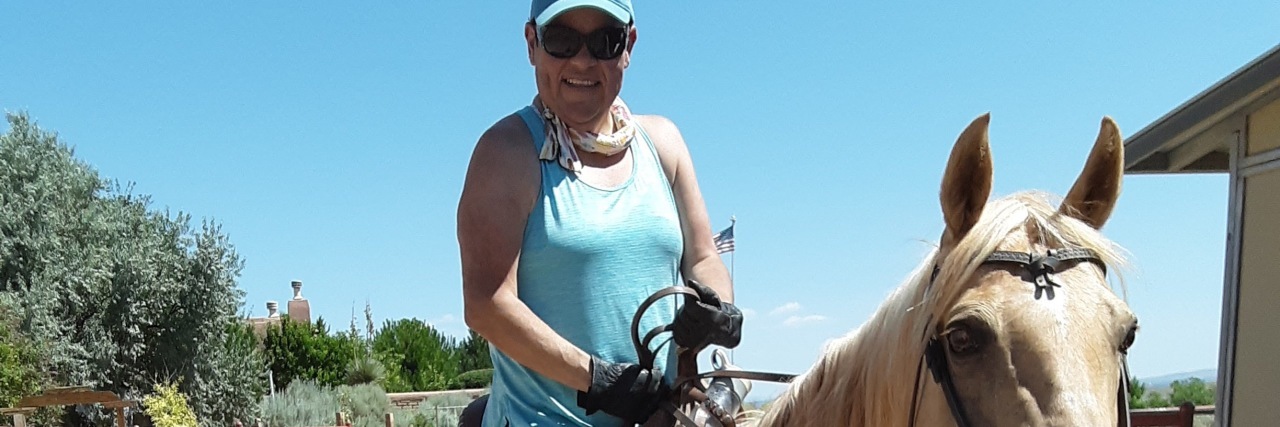 Cazandra riding a tan and cream horse.