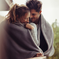 Man and woman standing together and wrapped in blanket