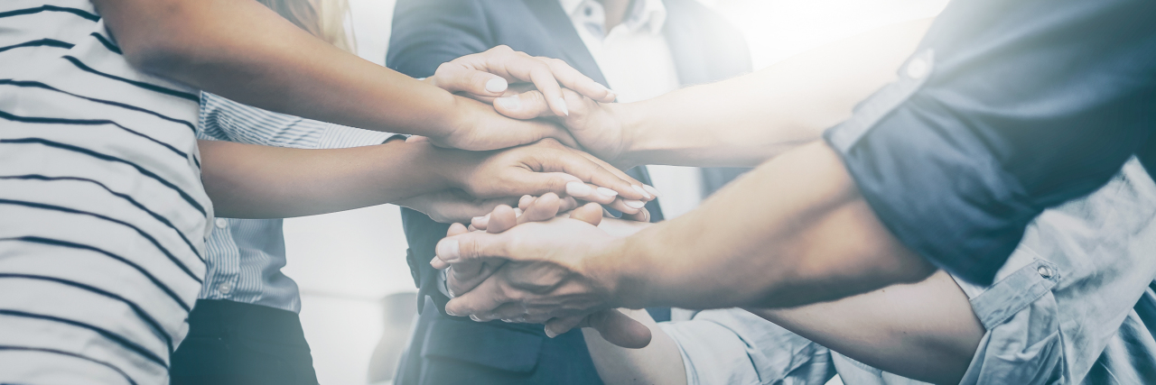 CEOs Need to Understand Workplace Mental Health Group of 8 hands stacked together of young businessmen and women