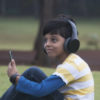 Boy with headphones and tablet at park.