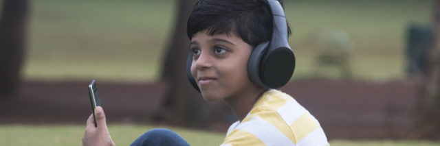 Boy with headphones and tablet at park.