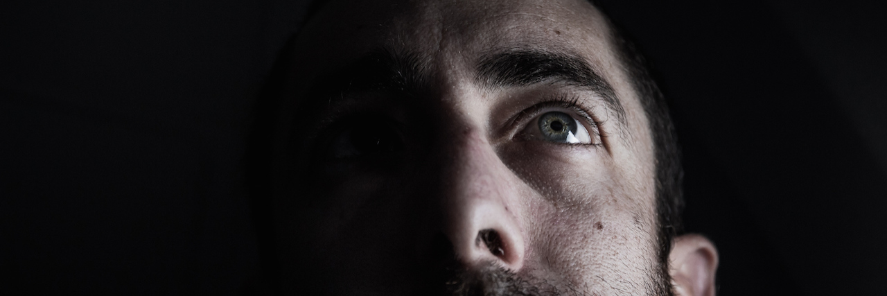 A dark portrait of a man looking up