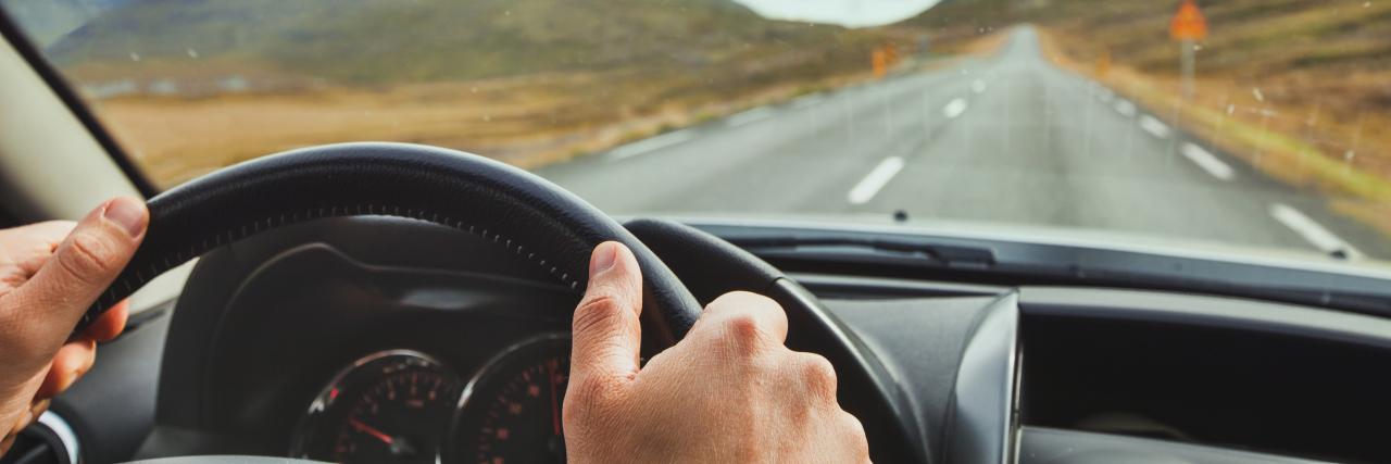 Traveling Long Distances for Rare Disease Treatment focus on someone's hands on the wheel of a car, with a wide open road