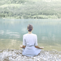 Woman doing yoga in front of a spectacular mountain lake.