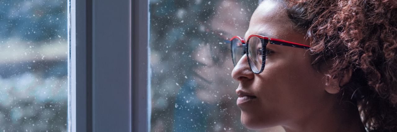 Loneliness in People With Chronic Illness and Disabilities Woman looking out window with sad expression.