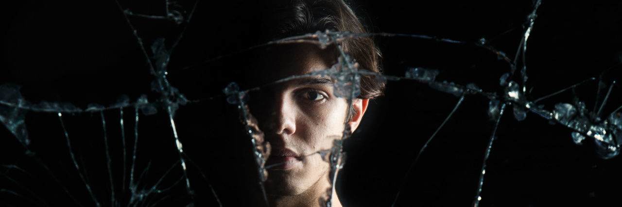 Impostor Syndrome From Having an Invisible Disability Woman reflected in cracked mirror.