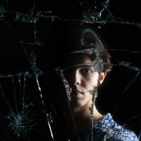Woman reflected in cracked mirror.