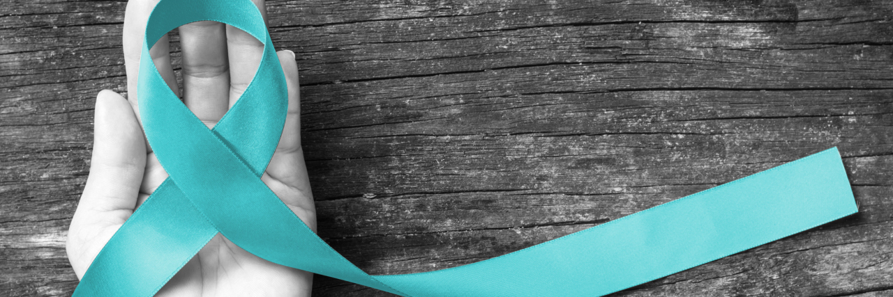 Why You Should Recognize Ovarian Cancer Awareness Month Teal ribbon awareness on woman's hand for Ovarian Cancer