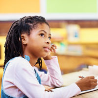 Contemplative girl writing notes in the classroom