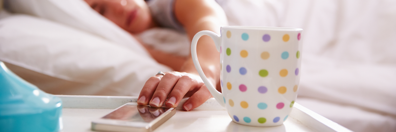 Tips for Coping With Chronic Fatigue and Loneliness woman in bed reaching for phone