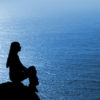 a woman meditating at the ocean