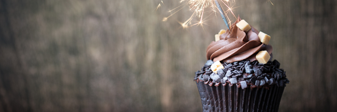 A chocolate cupcake with a sparkler for a birthday celebration.