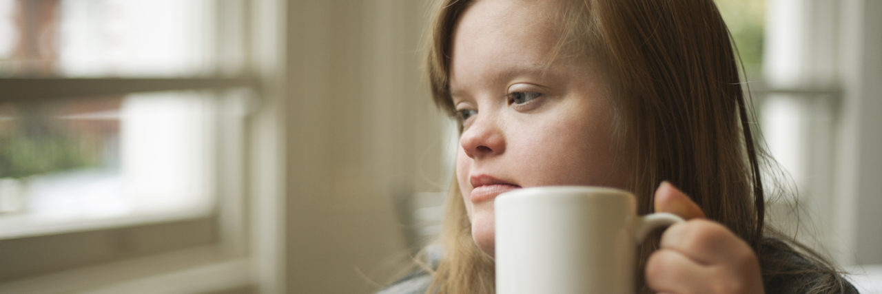 Portrait of girl with down syndrome having breakfast.