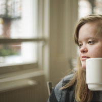 Portrait of girl with down syndrome having breakfast.