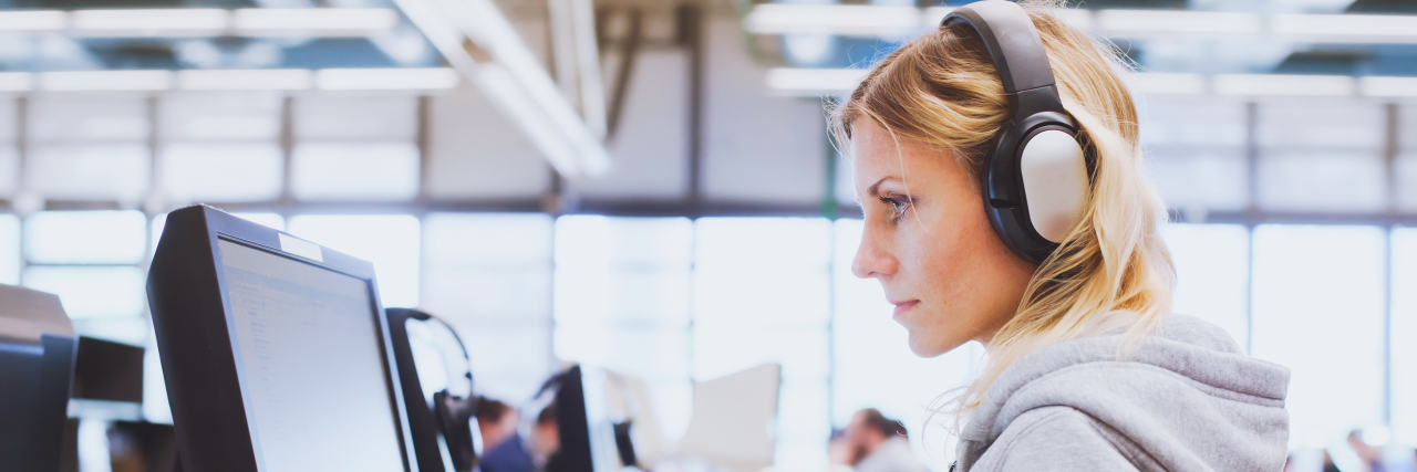 Workplace Accommodations When You Have Autism Woman wearing headphones working at computer.