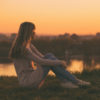 a woman is sitting watching the sunset