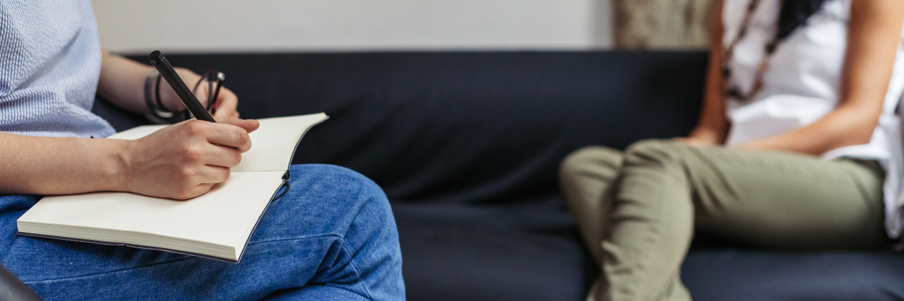 Medical PTSD and Chronic Illness: What to Know therapy session, two people sitting across from each other, one writing in a notebook