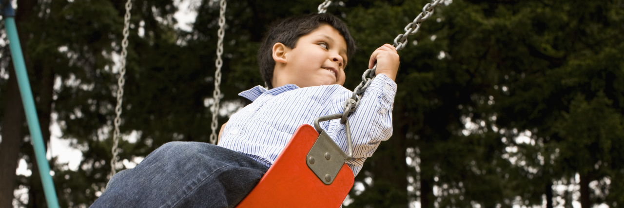 Boy looking over his shoulder while swinging.