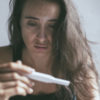 a sad woman holding a pregnancy test