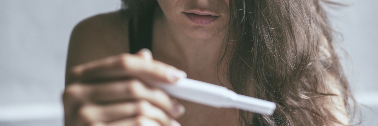 Living Through the Emotional Toll of Infertility a sad woman holding a pregnancy test