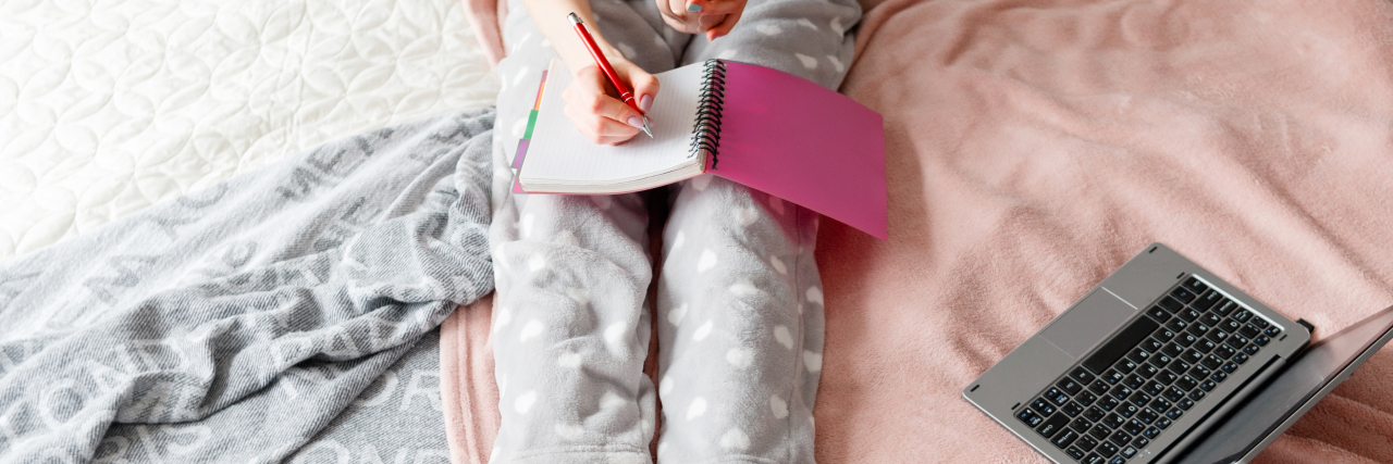 How to Create Structure and Achieve Goals With Chronic Illness woman in pajamas in bed with a computer and notebook